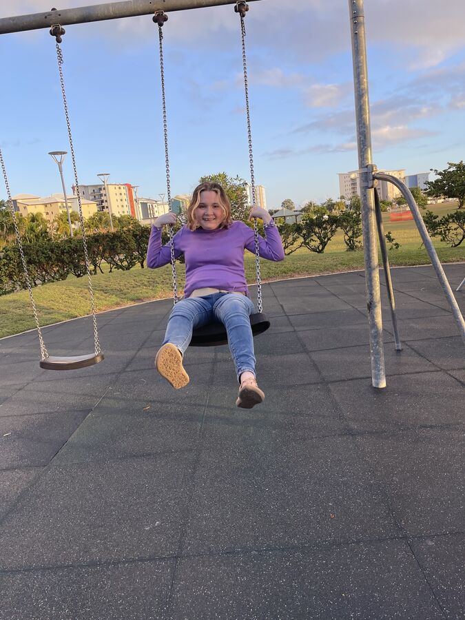 An Alfacare participant laughing on a swing